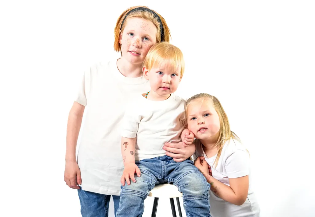 3 enfants de face, se tenant les uns aux autres. Fond blanc en arrière-plan