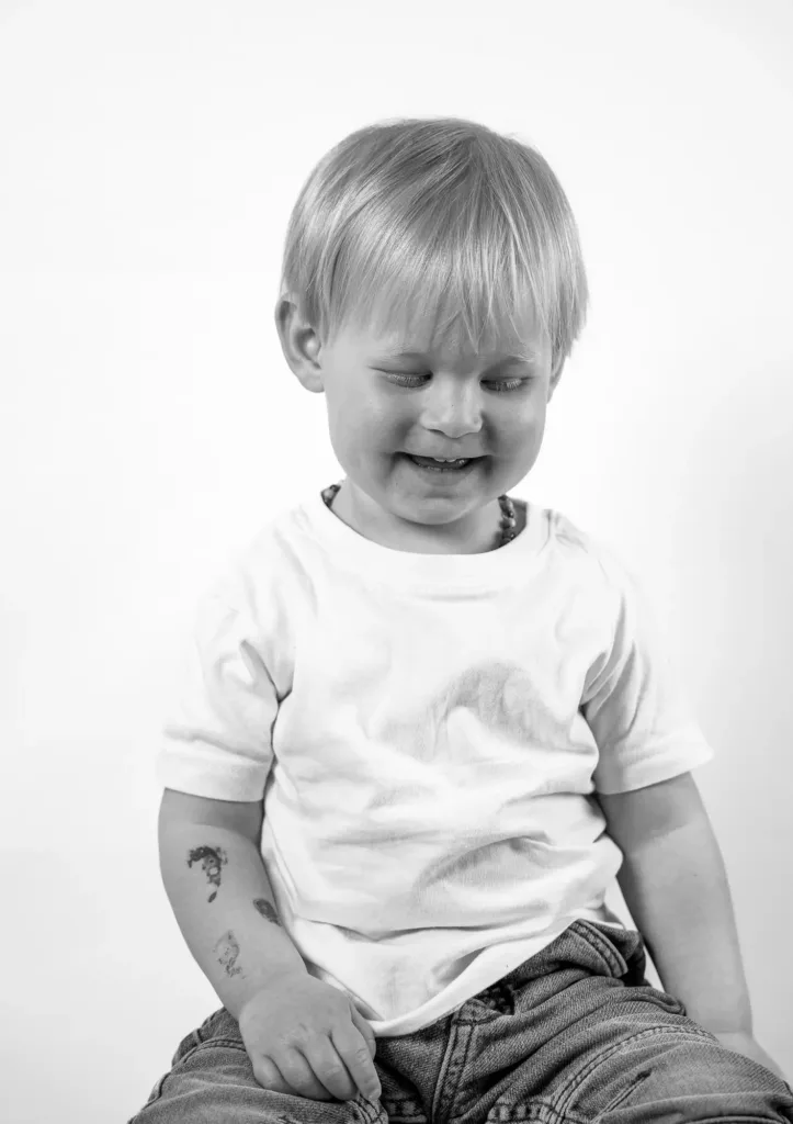Enfant souriant, assis sur un tabouret. Photo en noir & blanc