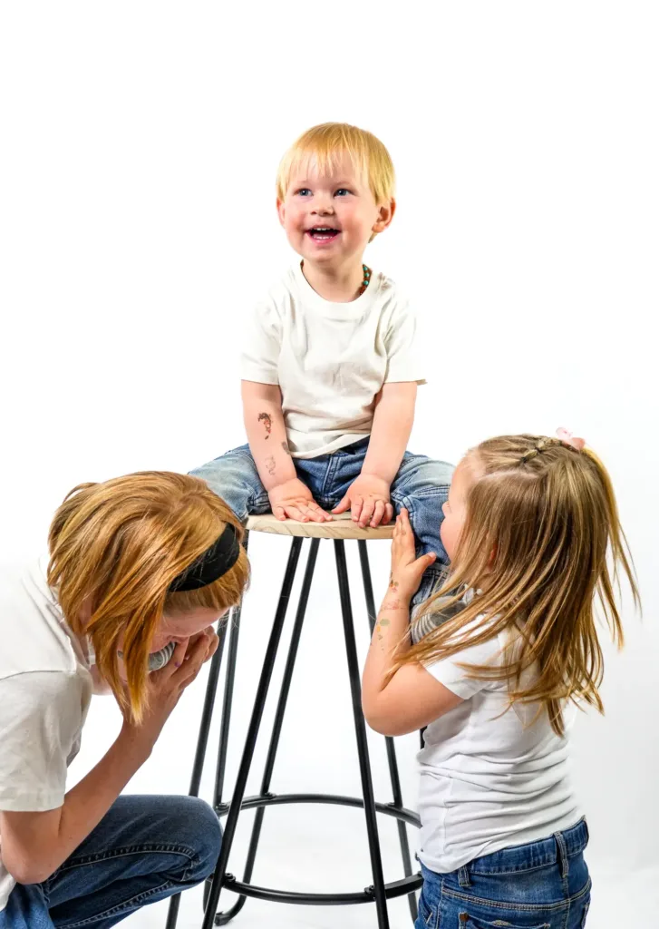 Photo d'un enfant assis sur un tabouret avec son frère et sa sœur de dos