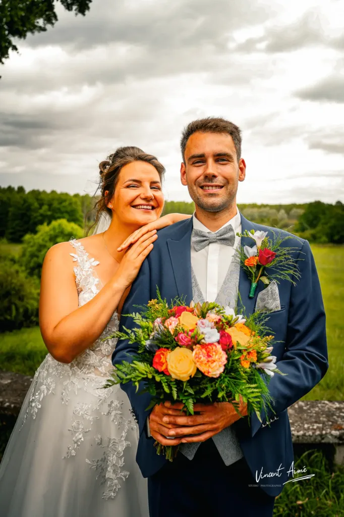Le marié tient le bouquet et la mariée est accoudée sur son épaule.