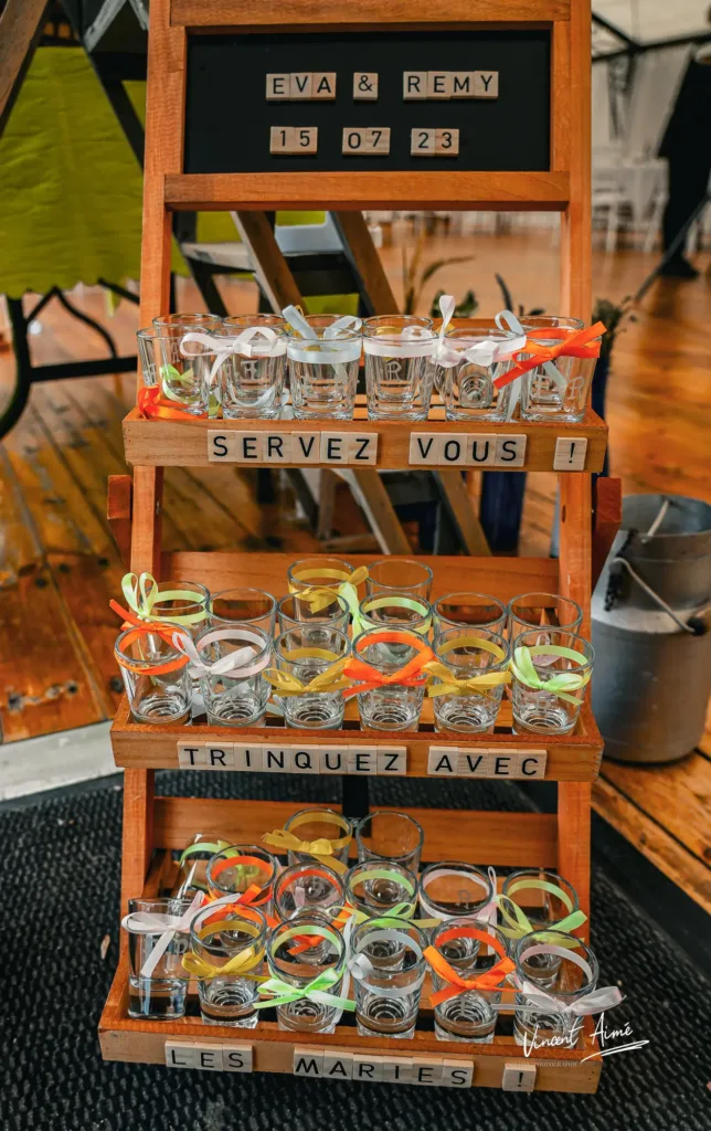Présentoirs avec des verres, indiquant : "Servez-vous, trinquez avec les mariés"