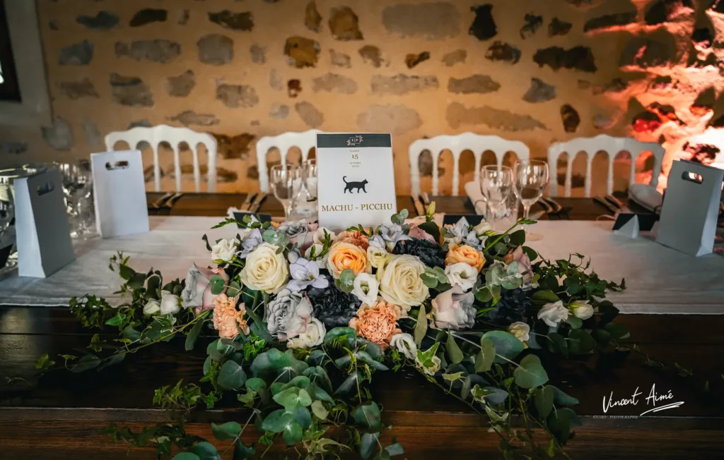 Table des mariés décorée avec un grand bouquet de fleurs et petit sachet souvenir
