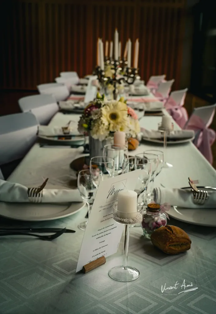 Table de réception dressée avec assiettes, couverts, menus et décorations de table.