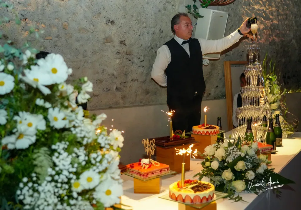Table remplit de desserts avec un serveur qui remplit une montagne de flûtes à champagne