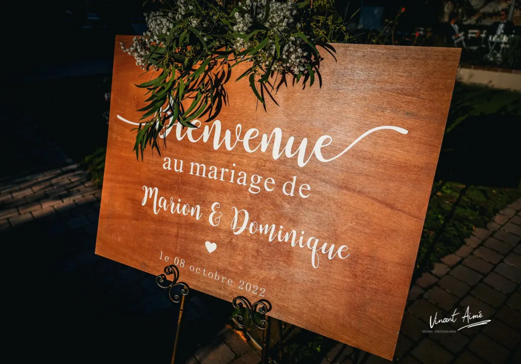 Panneau en bois indiquant "Bienvenue au mariage de Marion & Dominique"